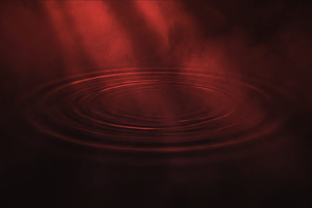 Concentric ripples spreading across still dark water